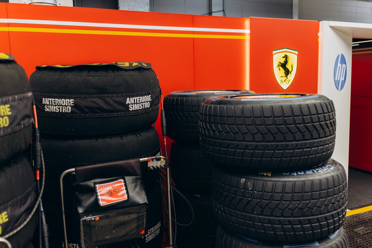 Stack of racing tires in Ferrari-themed garage, focus on motorsport equipment.