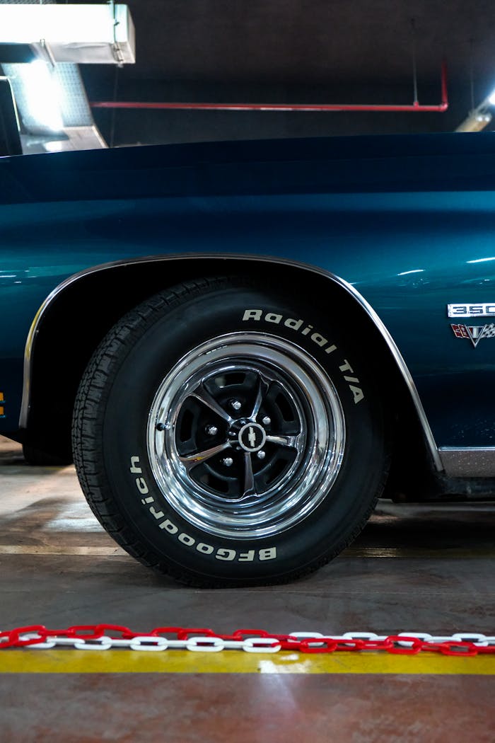 Detailed view of a classic car's wheel and tire in a garage setting.