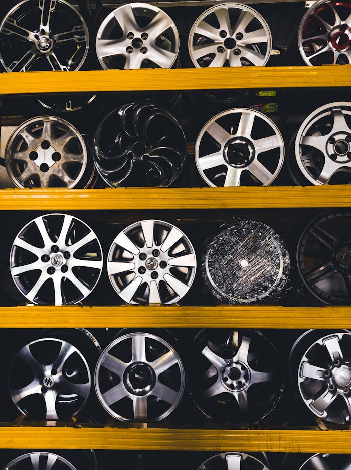 Vertical shot of various car rims displayed on shelves in Malaysia, showcasing different designs.