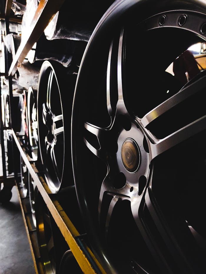 Close-up of stylish car rims arranged on shelves in a dimly lit warehouse.